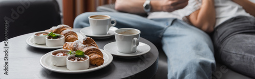 tasty croissants with jam and chocolate paste near coffee cups and cropped couple on blurred background  banner.