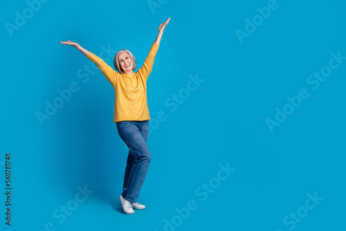 Full length photo of satisfied glad aged lady raise arms empty space novelty isolated on blue color background