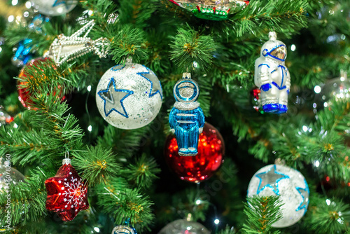 Christmas tree background and Christmas decorations in the mall. Colorful red balls,star,astronaut toys on green fir. New Year theme