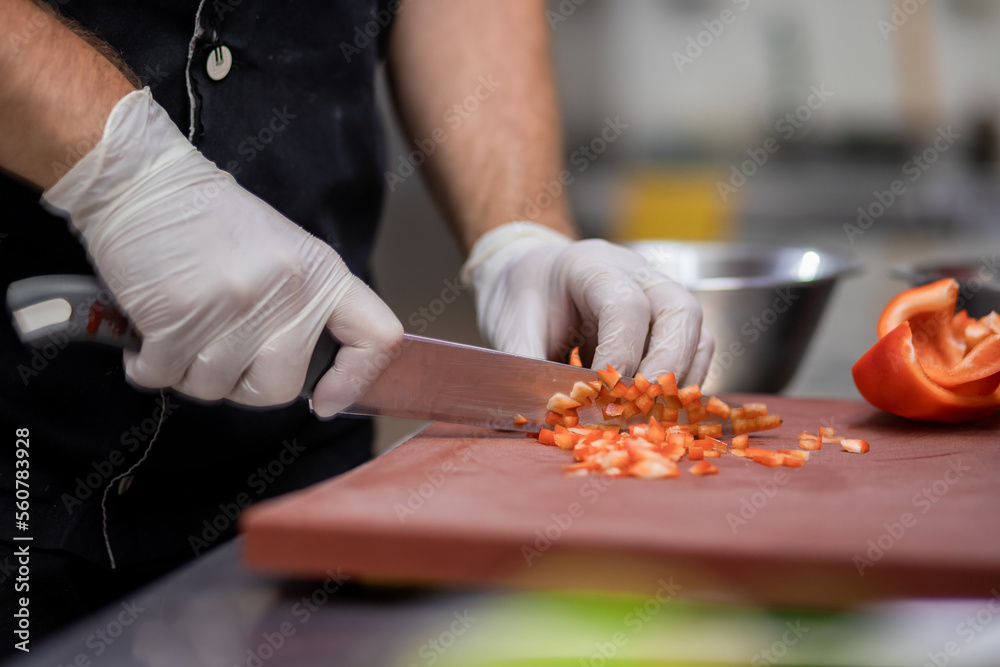 Professional chef in uniform preparing fresh vegetables on cutting board in restaurant kitchen. Culinary concept