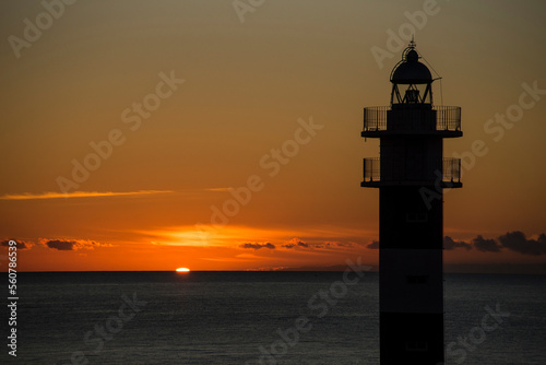 The Aguilas lighthouse at dawn with seagulls flying overhead