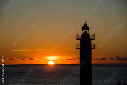 The Aguilas lighthouse at dawn with seagulls flying overhead