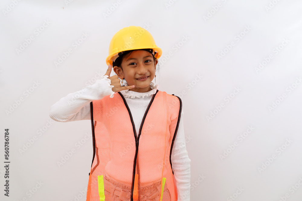Friendly Asian little girl in the construction helmet as an engineer showing talking on the phone gesture. Isolated on white