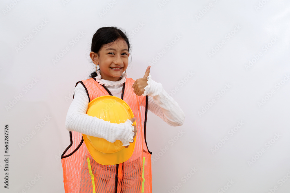 Happy Asian little girl in the construction helmet as an engineer standing while showing thumbs up. Isolated on white with copyspace Happy Asian little girl in the construction helmet as an engineer standing while showing thumbs up. Isolated on white with copyspace