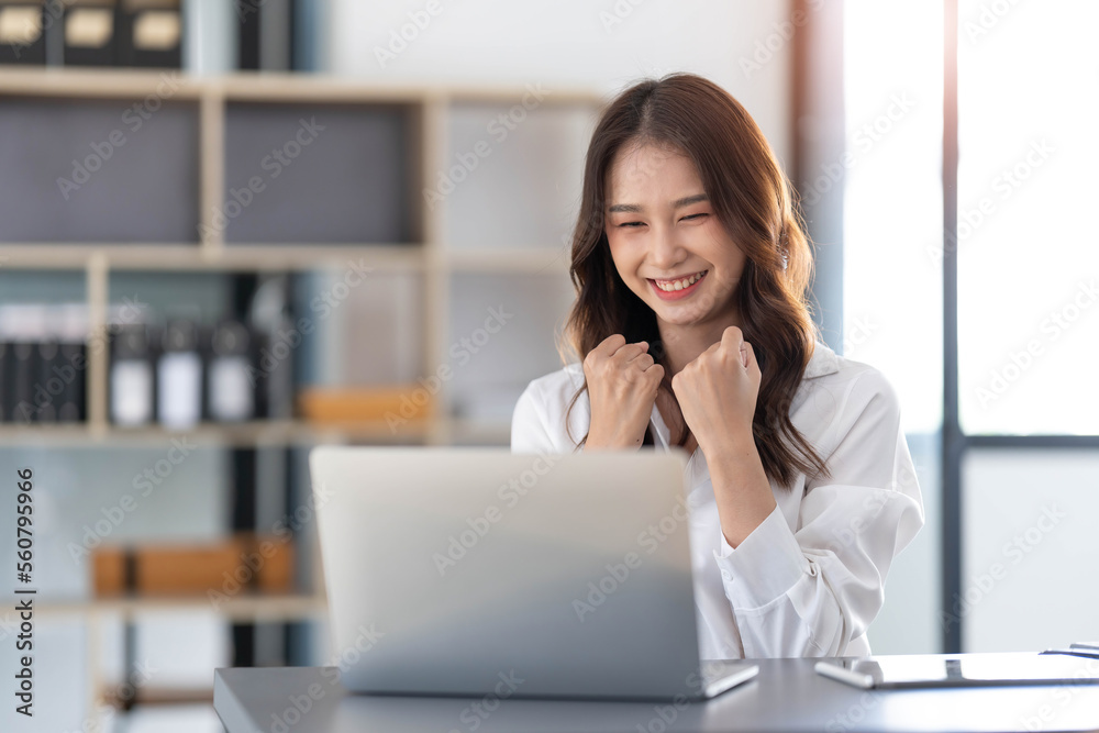 Beautiful asian woman using laptop computer, exciting and celebrating with good news of business successful. Small business startup concept.
