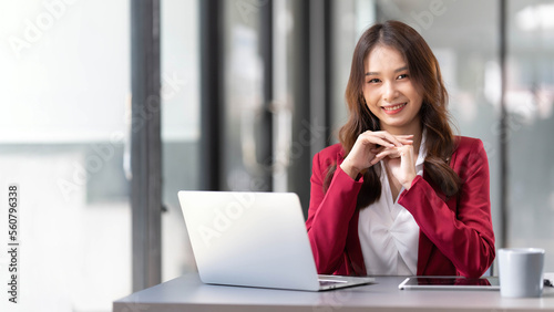 Portrait of smiling beautiful business asian woman in pink suit working in home office desk using computer. Business people employee freelance online marketing e-commerce, work from home concept