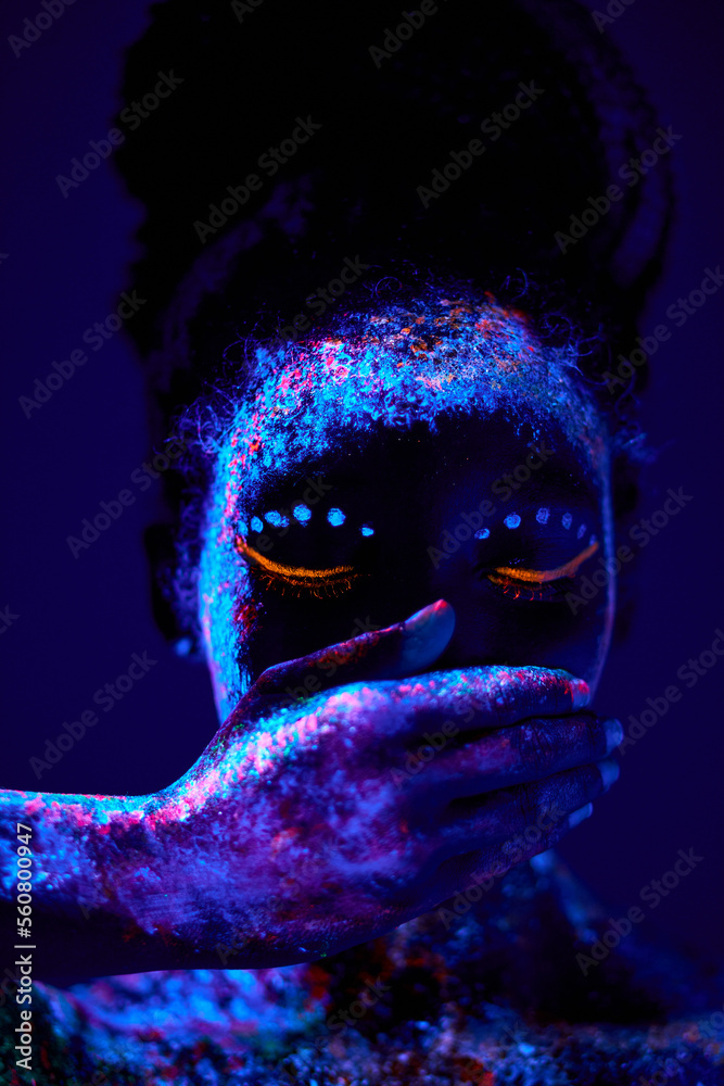 beautiful black woman with creative fluorescent prints paintings on skin,  on body, close mouth. cosmic art on body. neon lights, ultra-violet rays,  luminescence, silence, beauty concept Stock Photo