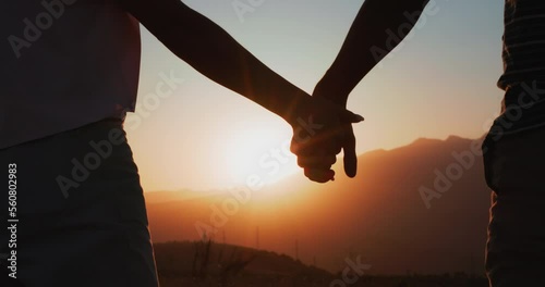 Silhouette of couple holding hands at sunset. Romantic couple in love, support each other concept. Closeup slowmotion
