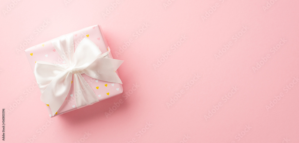 Valentine's Day concept. Top view photo of giftbox with white ribbon bow on isolated pastel pink background with copyspace