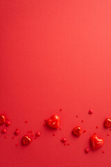 Valentine's Day concept. Top view vertical photo of heart shaped candies candles and sprinkles on isolated red background with copyspace