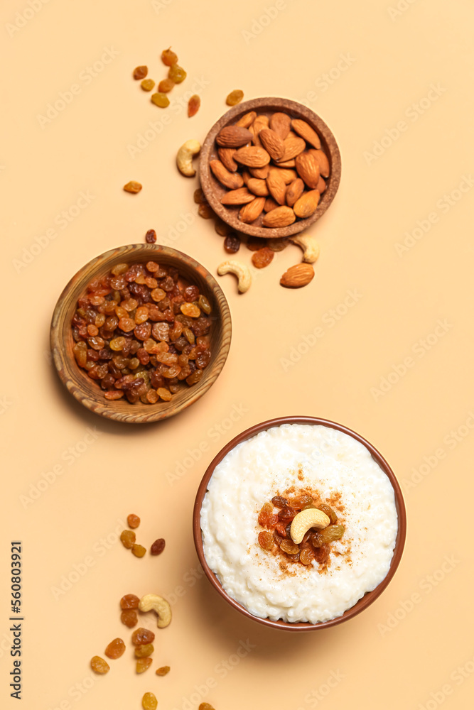 Bowl with delicious rice pudding, plates with raisins and almonds on beige background Bowl with delicious rice pudding, plates with raisins and almonds on beige background