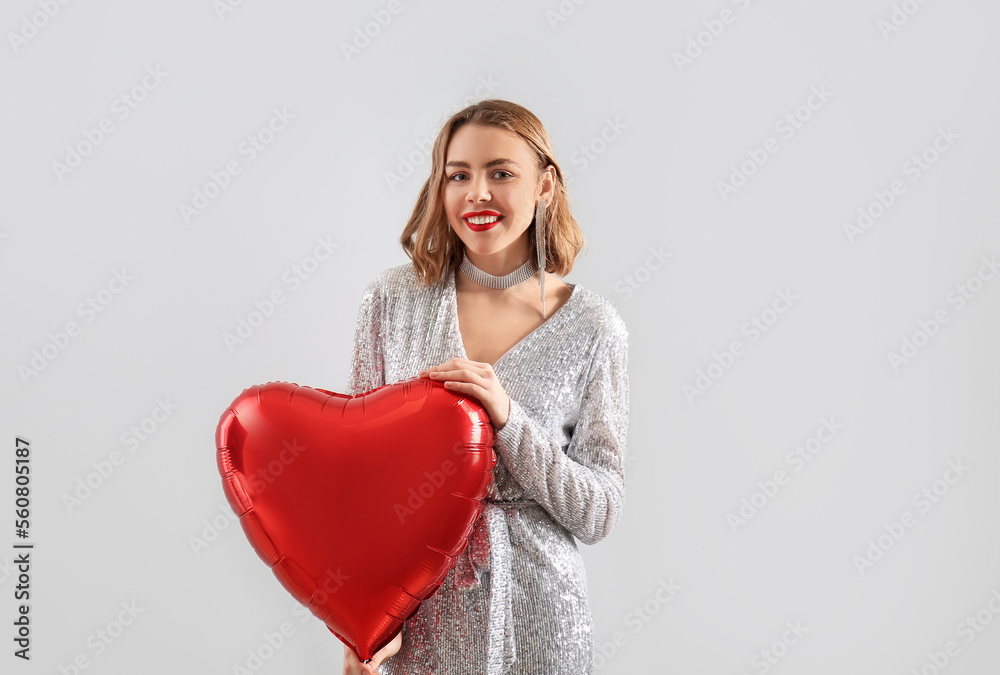 Beautiful young woman with red heart-shaped balloon on light background Beautiful young woman with red heart-shaped balloon on light background