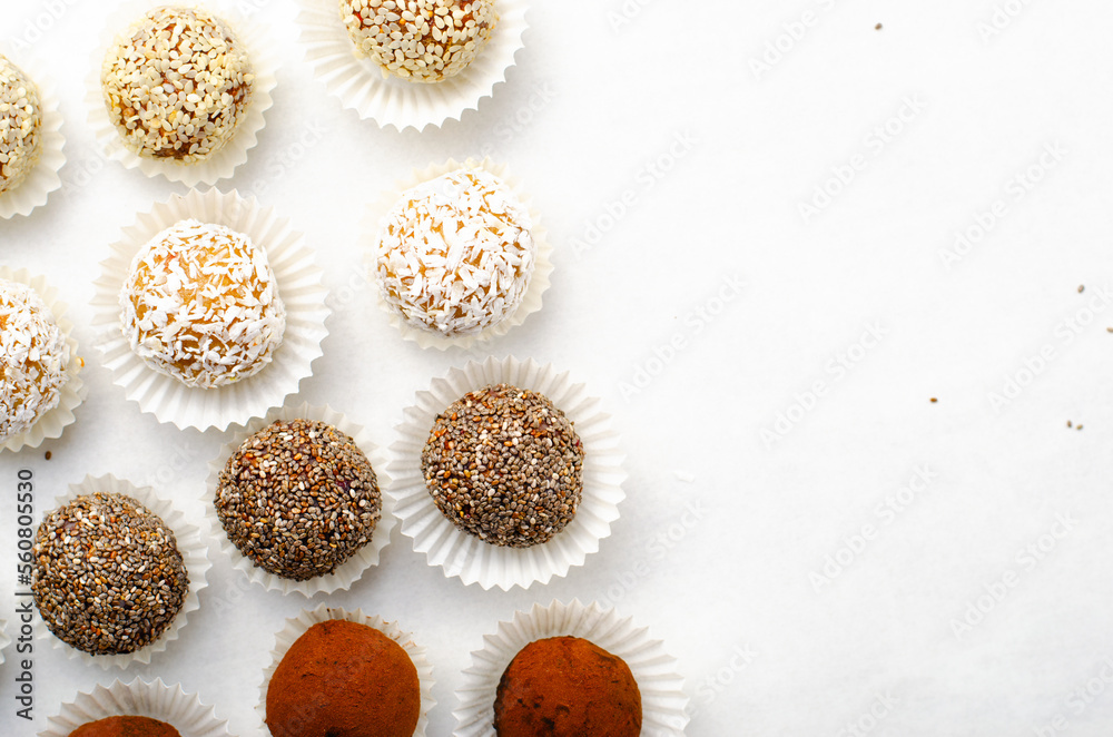 Fototapeta premium Assorted Vegan Sweets, Delicious Candy Balls with seeds, nuts and cocoa powder, Healthy Candies on Bright Background