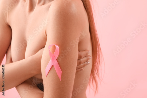 Naked young woman with pink ribbon on color background, closeup. Breast cancer awareness concept