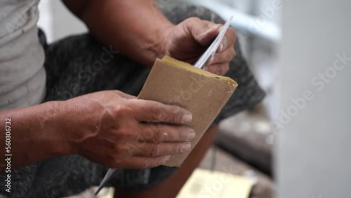 Close-up shot of a man sanding acrylic plate using sand paper