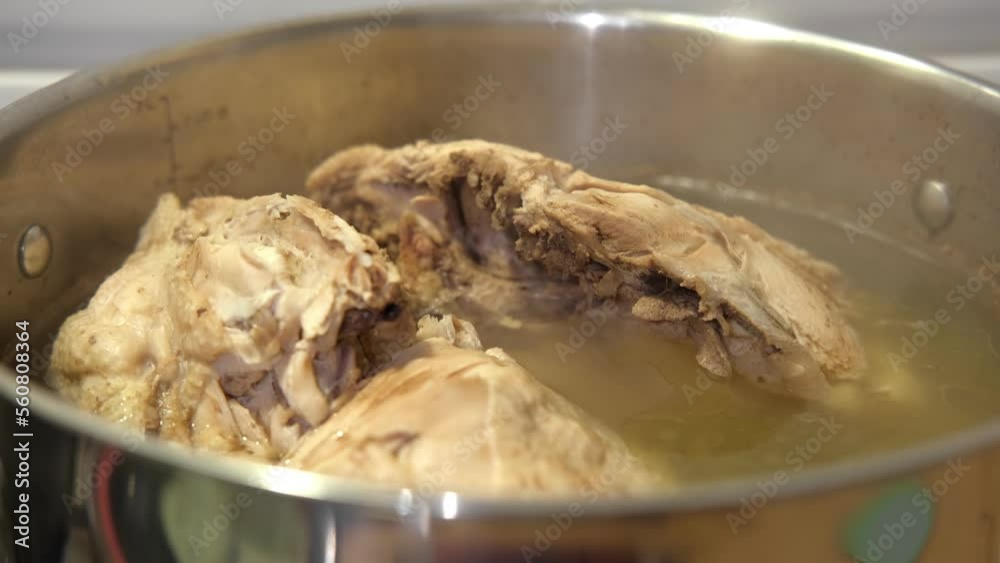 Saucepan with bouillon with a ladle on a wooden table. Bone broth. Chicken soup boiling with whole poultry. Preparing Clear soup with Meat. Cooking Bone broth making in a steel pot. Paleo diet. 4K