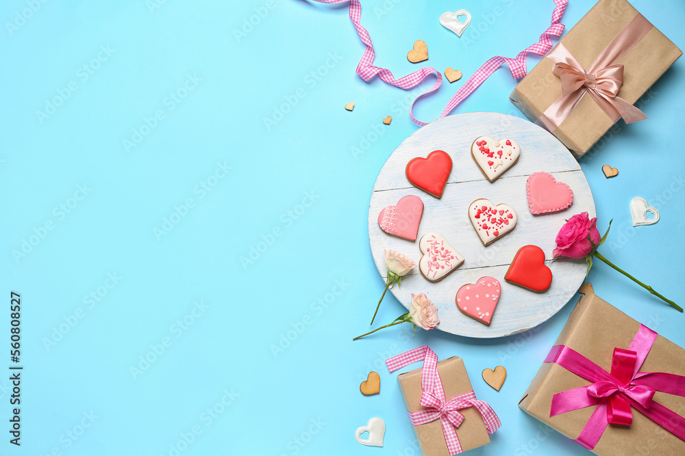 Composition with tasty heart shaped cookies, gift boxes and rose flowers on color background. Valentine's Day celebration
