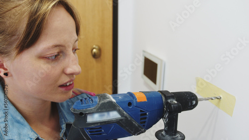 Caucasian woman drilling the wall, closeup. High quality photo