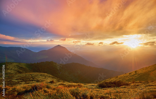 Stunning, picturesque sunrise in the summer mountains. Light morning mist glows beautifully in the rays of the rising sun. Beautiful mountain landscape
