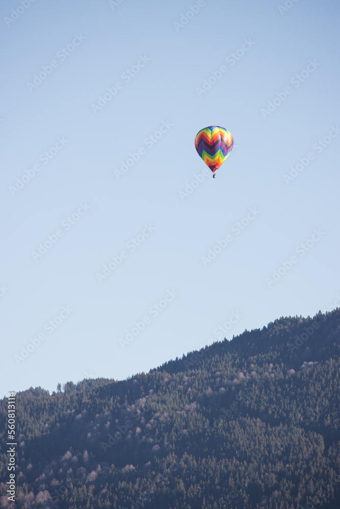 Colorful hot air balloon flying over mountain with clear sky and copy space