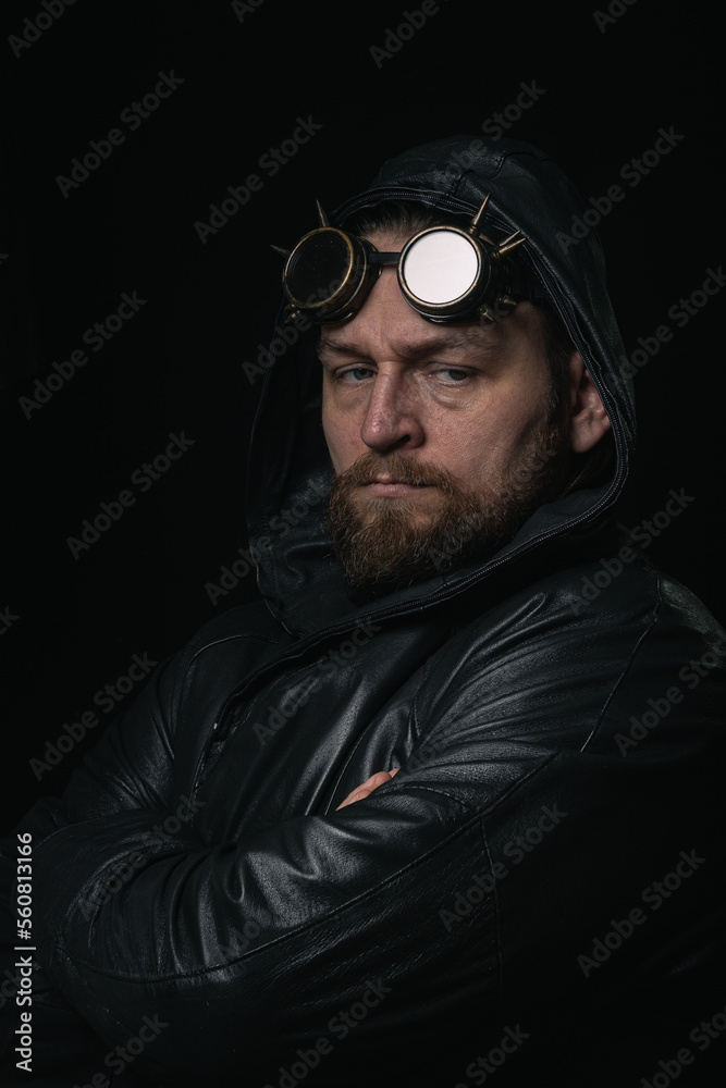 Obraz premium A man in a hood, wearing vintage steampunk goggles looking at the camera close-up