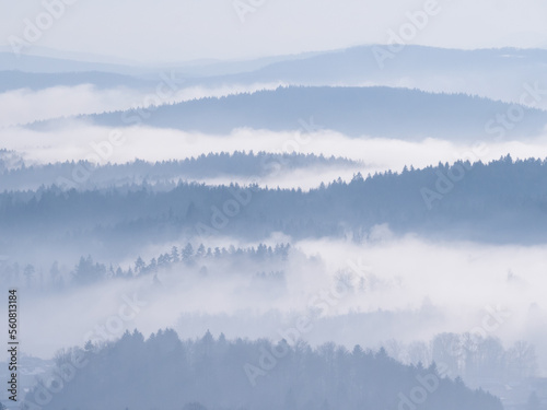 Winter fog rolling among forested hills creating beautifully layered landscape