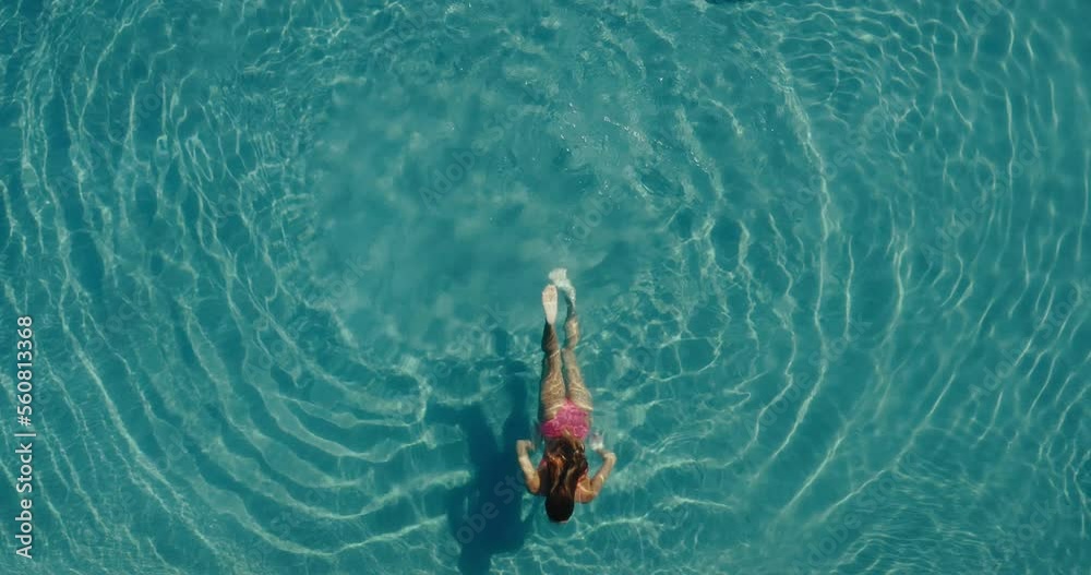 Aerial view of beautiful woman swimming in the the pool at luxury resort spa