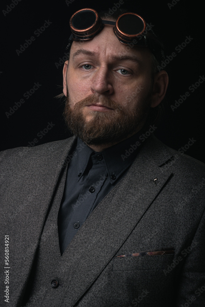 Obraz premium charismatic man in a classic suit and steampunk goggles on a black background stylish Portrait