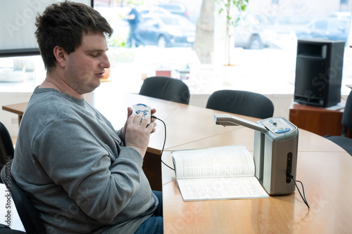 A visually impaired man uses a scanning and reading machine. photo