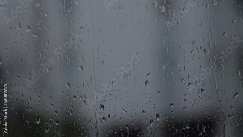 raindrops slowly running down the window glass, gray background