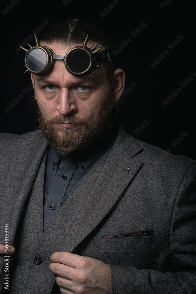 Fototapeta premium charismatic man in a classic suit and steampunk goggles on a black background stylish Portrait
