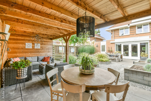 a patio with chairs, tables and plants on the table in front of an outdoor living room that has wood paneled walls
