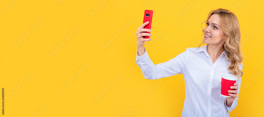 Woman isolated face portrait, banner with mock up copy space. cheerful blonde woman with coffee cup making selfie on phone on yellow background. Woman isolated face portrait, banner with mock up copy space. cheerful blonde woman with coffee cup making selfie on phone on yellow background.