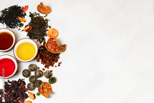 Black, green and red tea in round cups without handles on a light background from above with copy space surrounded by assorted tea leaves