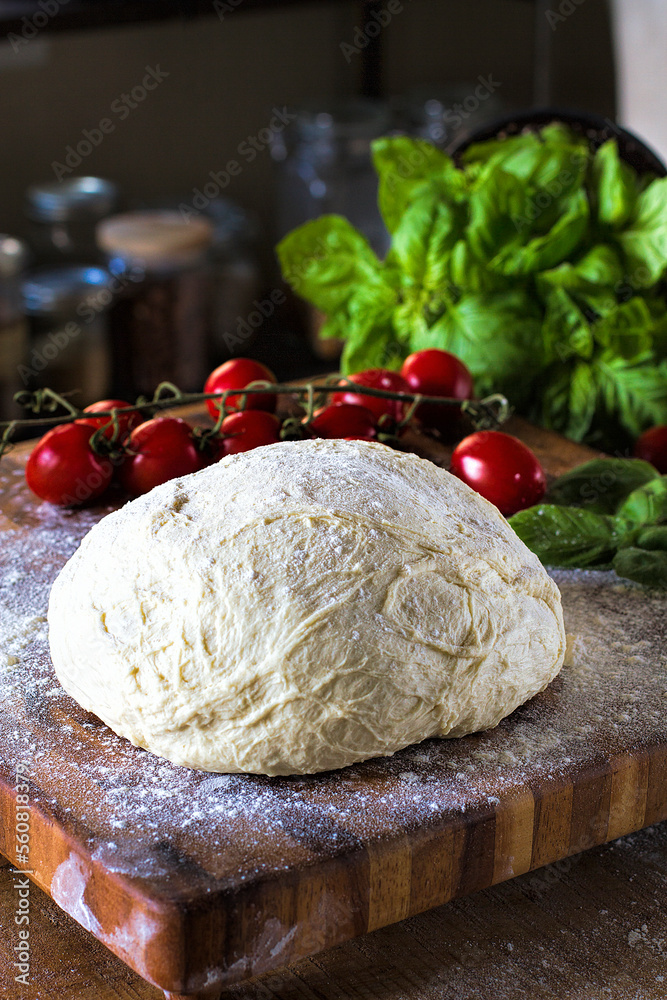 Fresh handmade pizza dough on a wood board with organic tomatoes and basil Fresh handmade pizza dough on a wood board with organic tomatoes and basil