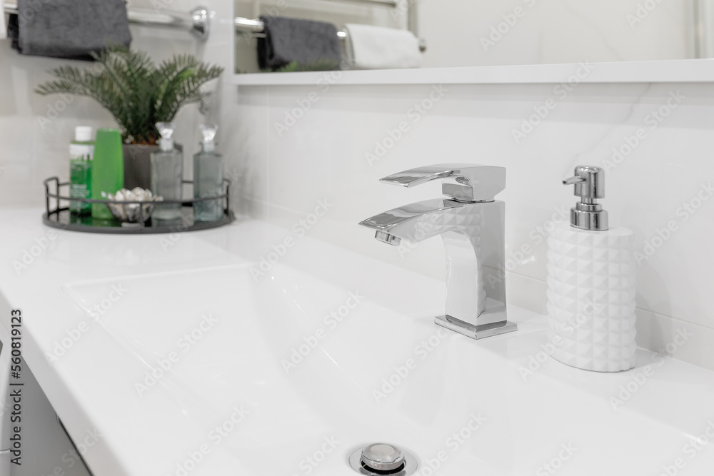 Fototapeta premium Water faucet mixer located in a modern, bright bathroom. Close-up