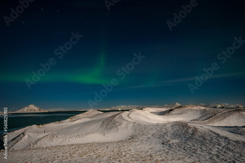 Aurora Borealis or Northern lights the amazing wonder of nature in the dramatic skies of Iceland. Night landscape with the green light and white snow of winter