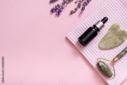 Fototapeta Naklejka Na Ścianę i Meble -  Massager for face skin, towel and dropper bottle with lavender flowers on colored background top view