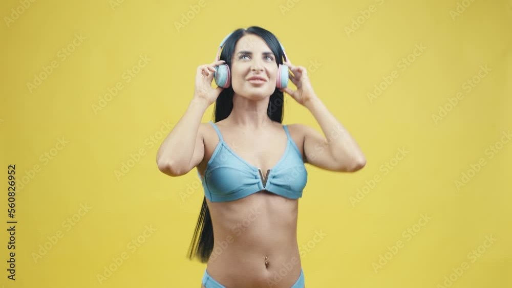 Beautiful young woman in headphones on a yellow background listening to music and dancing Beautiful young woman in headphones on a yellow background listening to music and dancing
