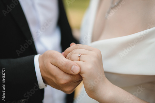 the groom tenderly holds the bride's hand close-up