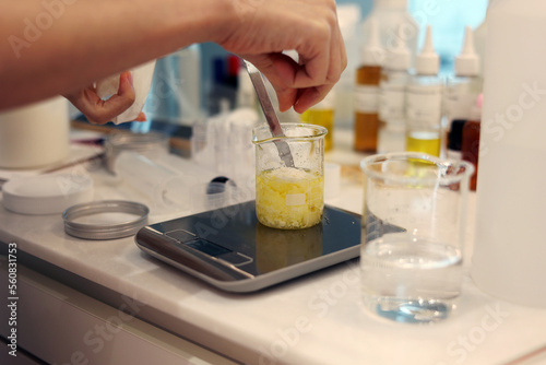 Put a beeswax in the beaker, weigh jojoba oil on the electronic scale in the laboratory photo