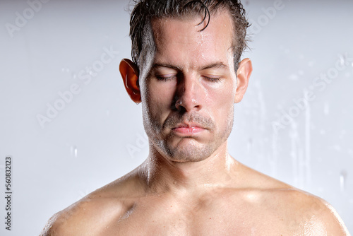 caucasian male taking shower in bathroom, relaxed man is upset, spending time in shower in the morning. handsome guy is dissatisfied with something, stand with eyes closed, wet and sexy naked body photo