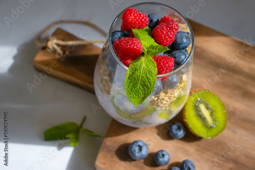 Yogurt, chia seeds, blueberries, strawberries, raspberries, mint, kiwi on a light background