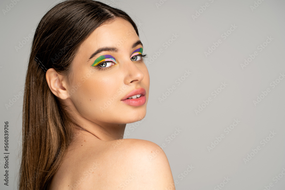 Teen model with colorful makeup looking at camera isolated on grey. Teen model with colorful makeup looking at camera isolated on grey.