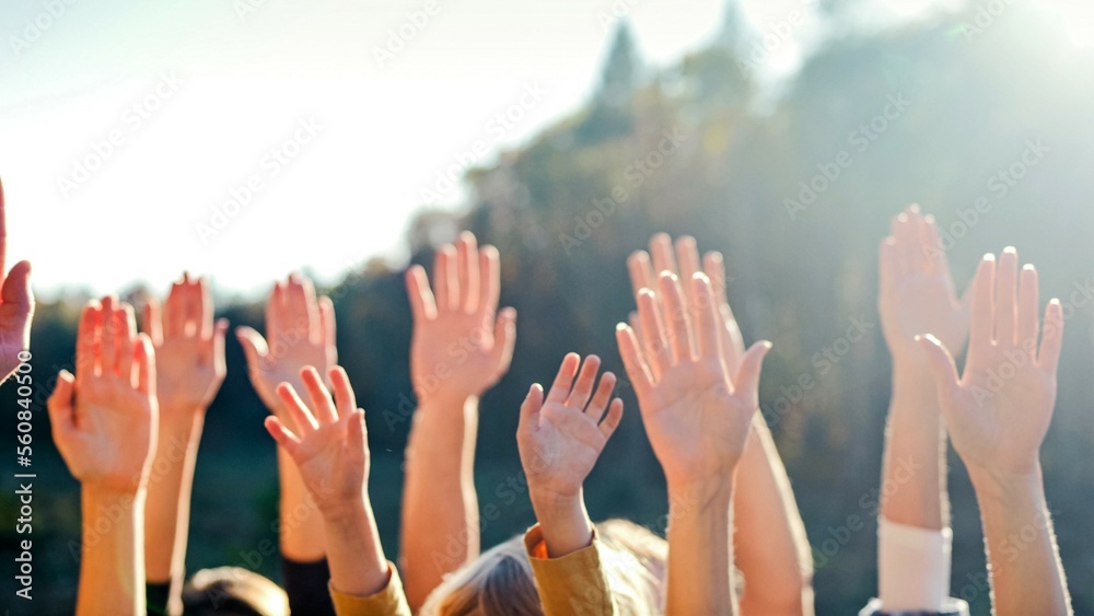 Close up of rising hands up in the air. Outdoor. Eco activism concept. People voting for safe environment. Males and females volunteers doing gesture of vote for global interaction in ecology.
