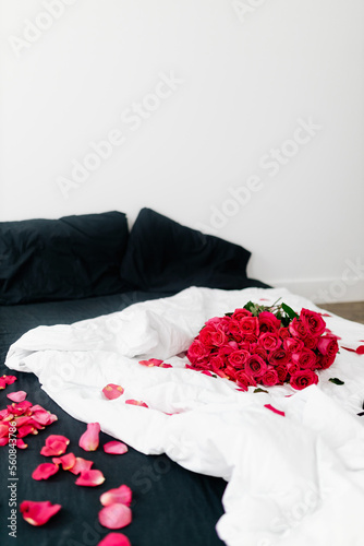 A beautiful bouquet of pink roses lies on a white and black bed. Background for Valentine's Day © Liudmila