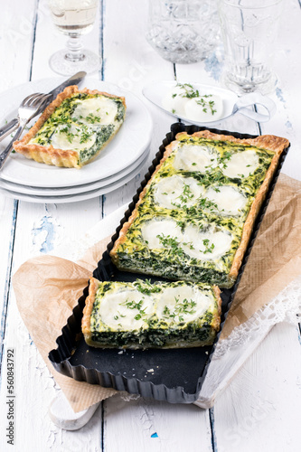 Traditional French tart with buffalo mozzarella and leaf spinach served as close-up in a backing form