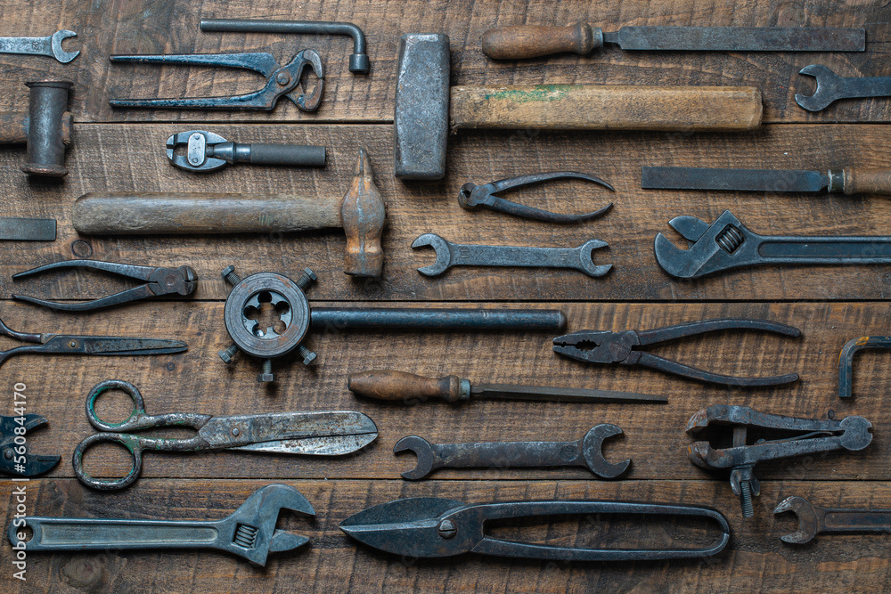 Vintage tools displayed on a background of wooden board, closeup, top view. Dirty set old working tools