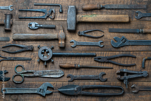 Vintage tools displayed on a background of wooden board, closeup, top view. Dirty set old working tools