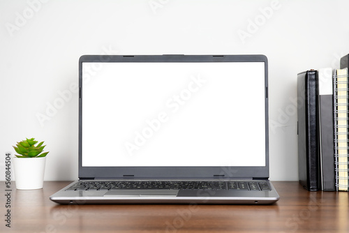 Home workplace with blank transparent screen laptop and books on wooden table with white wall background